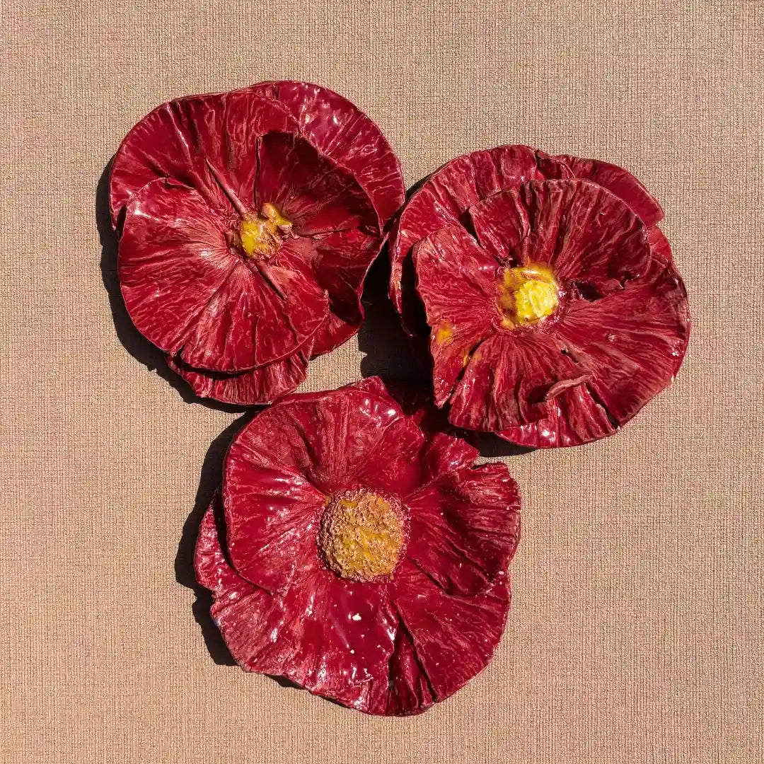 Handgemaakte rode klaprozen van keramiek, samen afgebeeld als muurkunst